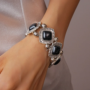Close-up of vintage silver bracelet with square black stones and embossed wave details