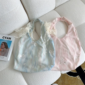 Detail of light blue and pink embroidered canvas tote bags with delicate lace bows