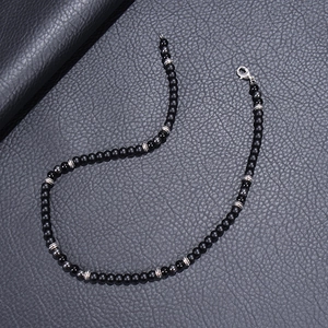 Vintage matte black stone beaded necklace with silver spacers on leather background