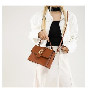Close-up of brown vintage leather handbag with gold buckle shown on a model