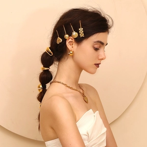 Close-up of a model wearing 18K gold-plated zircon scallop hair clips and heart earrings