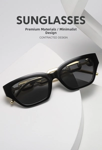 Detailed shot of black cat-eye sunglasses with thick gold chain link metal temples