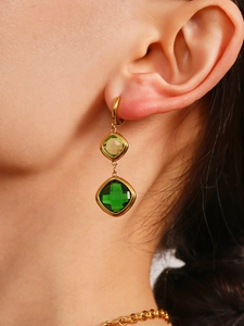 Close-up of square cut emerald glass earrings on model with golden plating detail