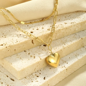 Detail view of 18K gold double layer chain necklace featuring a solid heart pendant