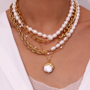 Detail of layered gold titanium steel necklace with white baroque pearl pendants