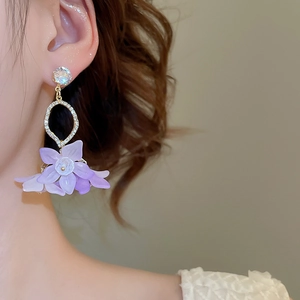 Macro shot of purple floral petal drop earrings with crystal accents on female model