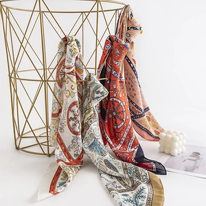 Elegant floral print square silk scarf draped gracefully from a gold geometric basket