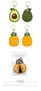 Macro view of cute cartoon avocado and pineapple leather keychains with golden clasps