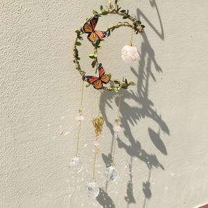 Macro detail of crescent moon suncatcher with crystal prisms reflecting rainbow light
