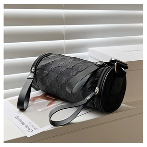 Detail of a black cylinder crossbody bag with bubble texture on a minimalist white window sill