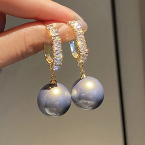 Detailed close-up of champagne pearl drop earrings with sparkling gold metal hoop setting