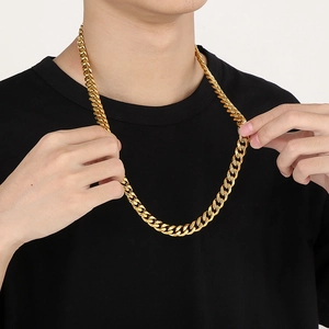 Close-up of a bold gold Cuban link necklace featuring sparkling rhinestones on model