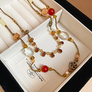 Détail du collier vintage avec perles en résine et fleur en céramique sur fond blanc