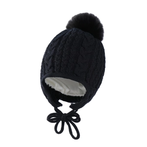 Detail view of black knit baby hat with warm white fleece lining and soft pom-pom