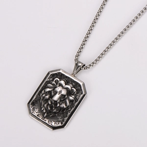 Close-up of embossed lion head square pendant on stainless steel box chain necklace