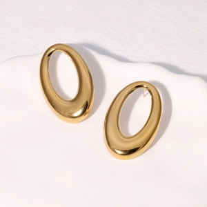 Minimalist gold oval hoop earrings with polished mirror finish on a ceramic tray