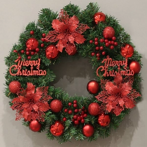 Detailed close-up of a Christmas wreath with red flowers, berries, and Merry Christmas sign