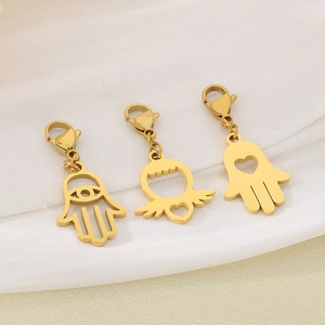 Détails de pendentifs main de Fatma dorés et d'ailes de cœur sur tissu blanc