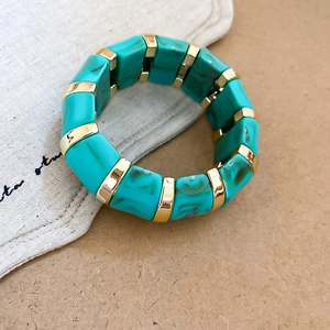 Detail of turquoise marble resin beads and gold metal spacers on an elastic bracelet