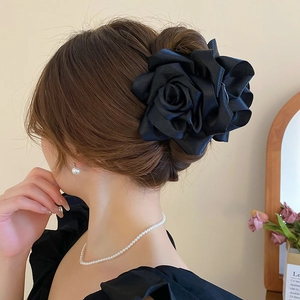 Détail d'une élégante pince à cheveux en forme de rose de satin noir sur un chignon stylé
