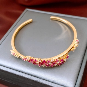 Détail macro du jonc vague en or 18 carats avec pierres rouges et roses sur soie