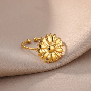Close-up of golden daisy ring with twisted rope band on elegant champagne satin fabric