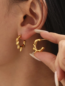 Detailed view of gold irregular lava-textured C-shape hoop earrings on a model