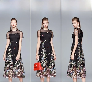 Detail view of a black A-line dress featuring colorful floral embroidery and mesh panels