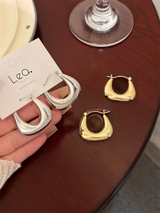 Détail de boucles d'oreilles épaisses en U en métal poli doré et argenté minimaliste