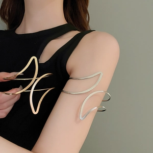 Détail de bracelets de bras géométriques ondulés en finitions métal or et argent poli