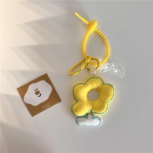 Macro detail of yellow plush flower keychain with blue embroidery and acrylic chain
