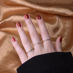 Three minimalist gold rings with green, white, and blue gemstones on fingers