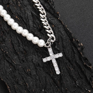 Cuban chain and pearl necklace with a sparkling cross pendant on a dark texture