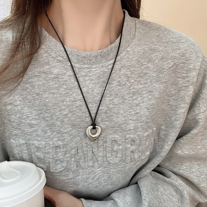 Close-up of a vintage hollow heart pendant necklace with a black cord on a model