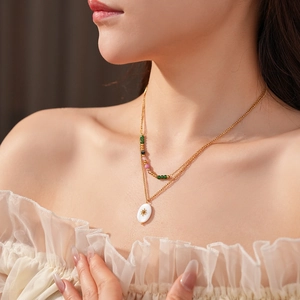 Close-up of a layered gold necklace with sun star oval pendant and colorful beads on model