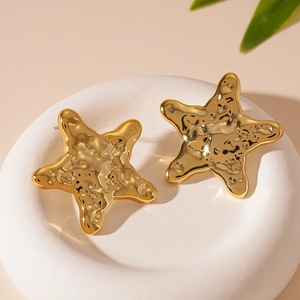 Detailed view of golden starfish stud earrings with a textured hammered metal finish