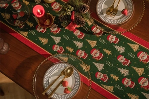 Green Christmas table runner featuring embroidered Santa Claus and trees on festive table