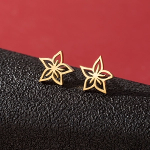 Paire de boucles d'oreilles étoiles évidées en acier doré sur une surface texturée