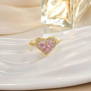 Detailed view of a gold-plated ring with a heart-shaped pink gem and pavé diamonds