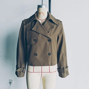 Détail d'un trench-coat court à double boutonnage avec revers classiques et sergé kaki
