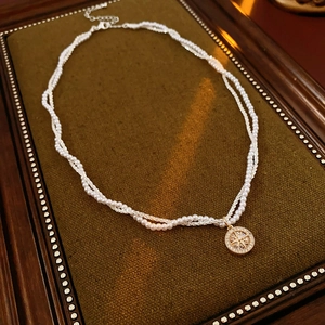Close-up of double layer pearl necklace with golden star compass pendant on vintage base