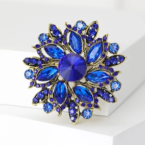 Detailed macro view of a vintage floral brooch with blue crystals and gold-tone metal