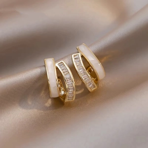 Close-up of gold-plated intertwined earrings with pearl petals and zircon crystals