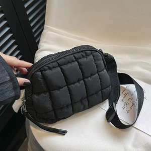 Close-up of black quilted crossbody bag with adjustable nylon strap and zipper detail