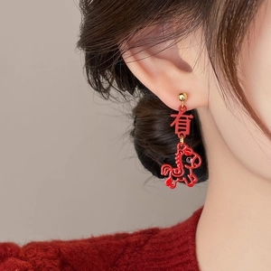 Macro shot of a red horse pendant earring with golden character bead for festive style