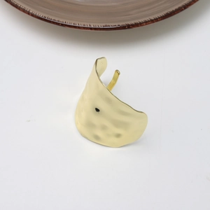Detail view of the hammered gold texture and irregular wavy edges on the metal hair clip
