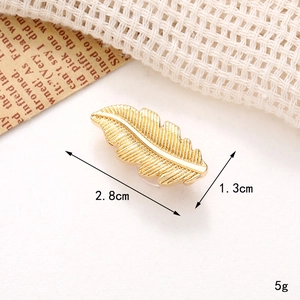 Detail of golden feather shoe charm showing dimensions 2.8cm by 1.3cm on a soft background