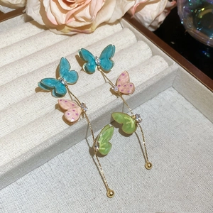 Detail of colorful enamel butterfly tassel earrings with zircons in a jewelry box
