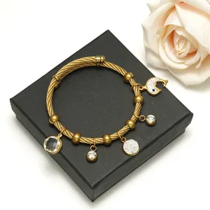 Golden woven steel wire bracelet featuring a crystal moon charm and diamond pavé pendant