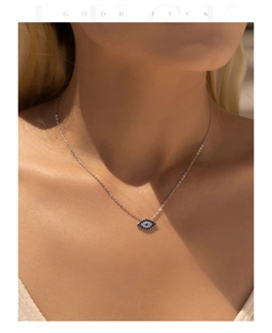 Macro detail of a silver Evil Eye necklace with blue pavé stones on a model's neck